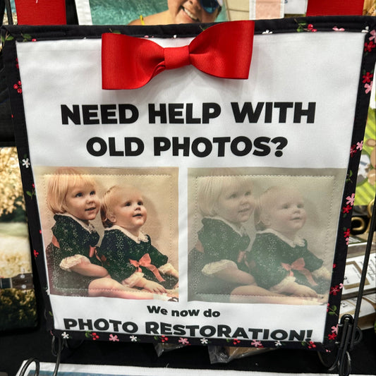 Promotional sign for photo restoration services with a red bow, surrounded by various photos.
